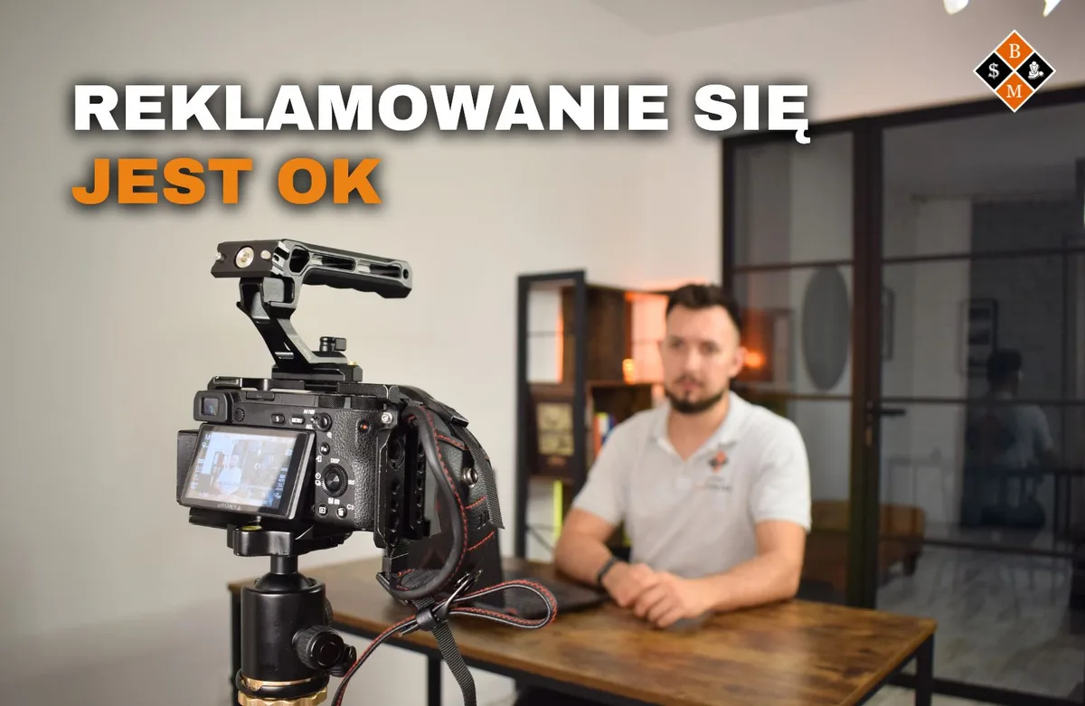 Aparat na statywie nagrywa masażystę przy biurku, napis „Reklamowanie się jest OK”