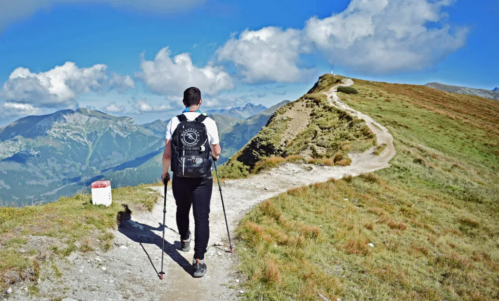 Karol Sobczyk z kijkami trekkingowymi idzie górskim szlakiem w Tatrach