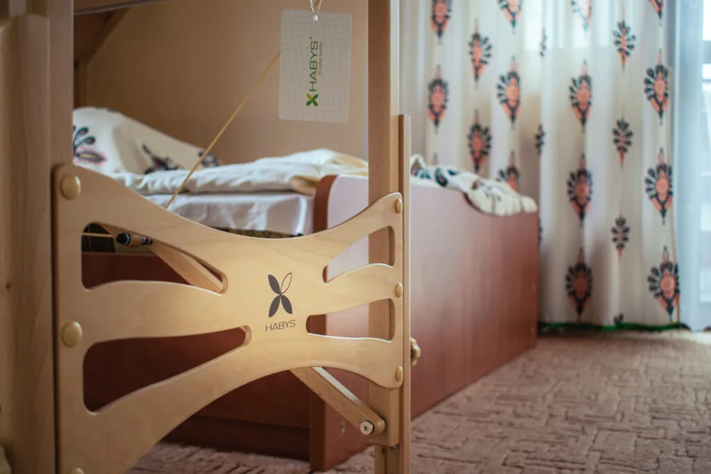 Drewniane nogi stołu do masażu Habys z metką producenta w pokoju hotelowym