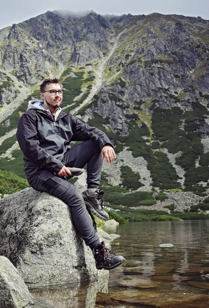 Karol Sobczyk siedzi na głazie nad górskim jeziorem w Tatrach podczas urlopu