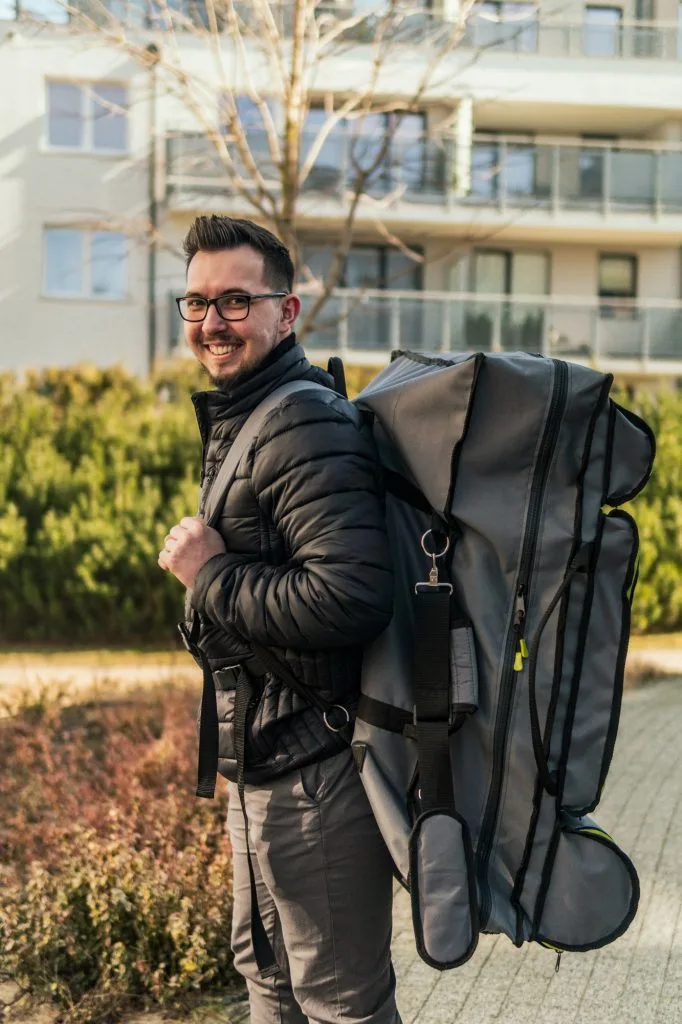 Uśmiechnięty masażysta niesie stół do masażu w pokrowcu-plecaku Habys City