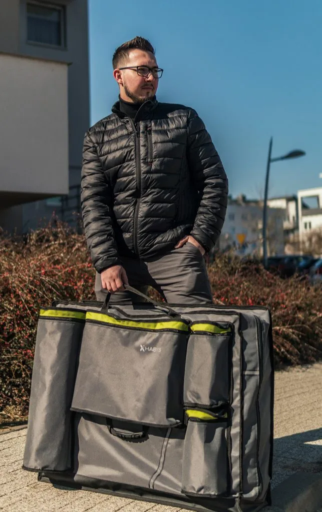 Masażysta trzyma szary pokrowiec na stół do masażu Habys City za rączkę